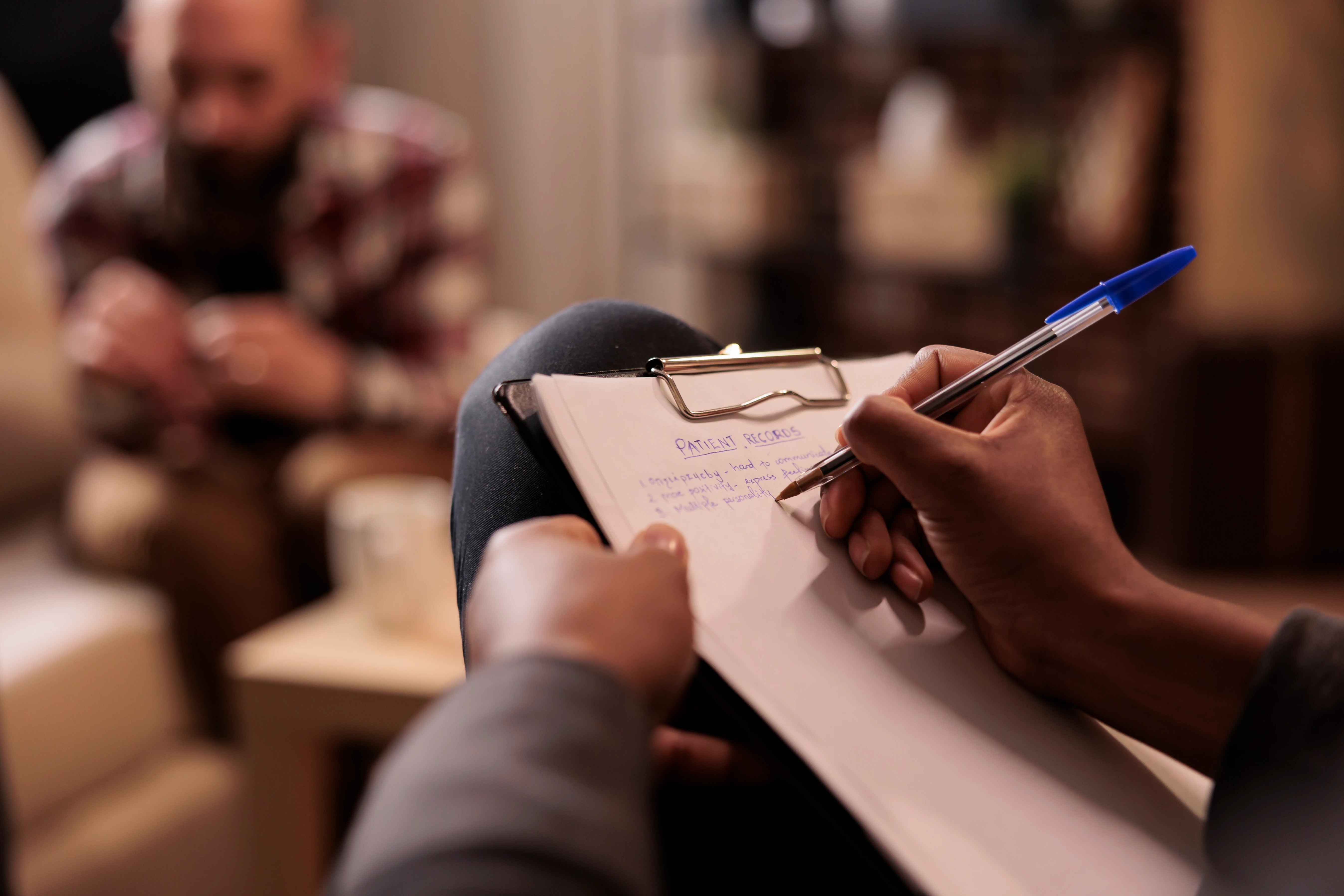 Clinician taking notes while guiding a couple through therapy